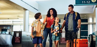 family traveling walking through an airport with carry on luggage