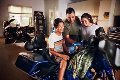 Close-up of dad teaching his kids about his motorcycle